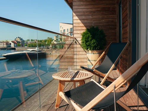 Balkong med två solstolar och ett litet bord på Slottsholmens flytande hotellrum, med utsikt över vattnet.